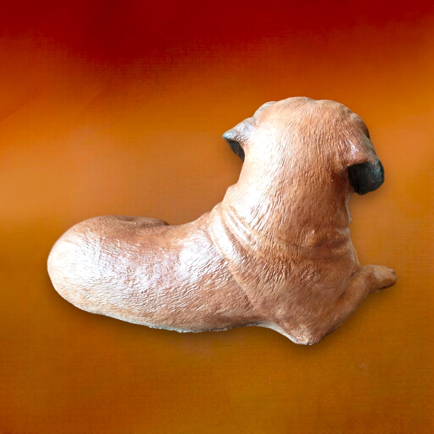 Bull Mastiff statue made of concrete and hand painted. Dog statue is laying down. Carmel brown colour with black snout and ears. Back of statue