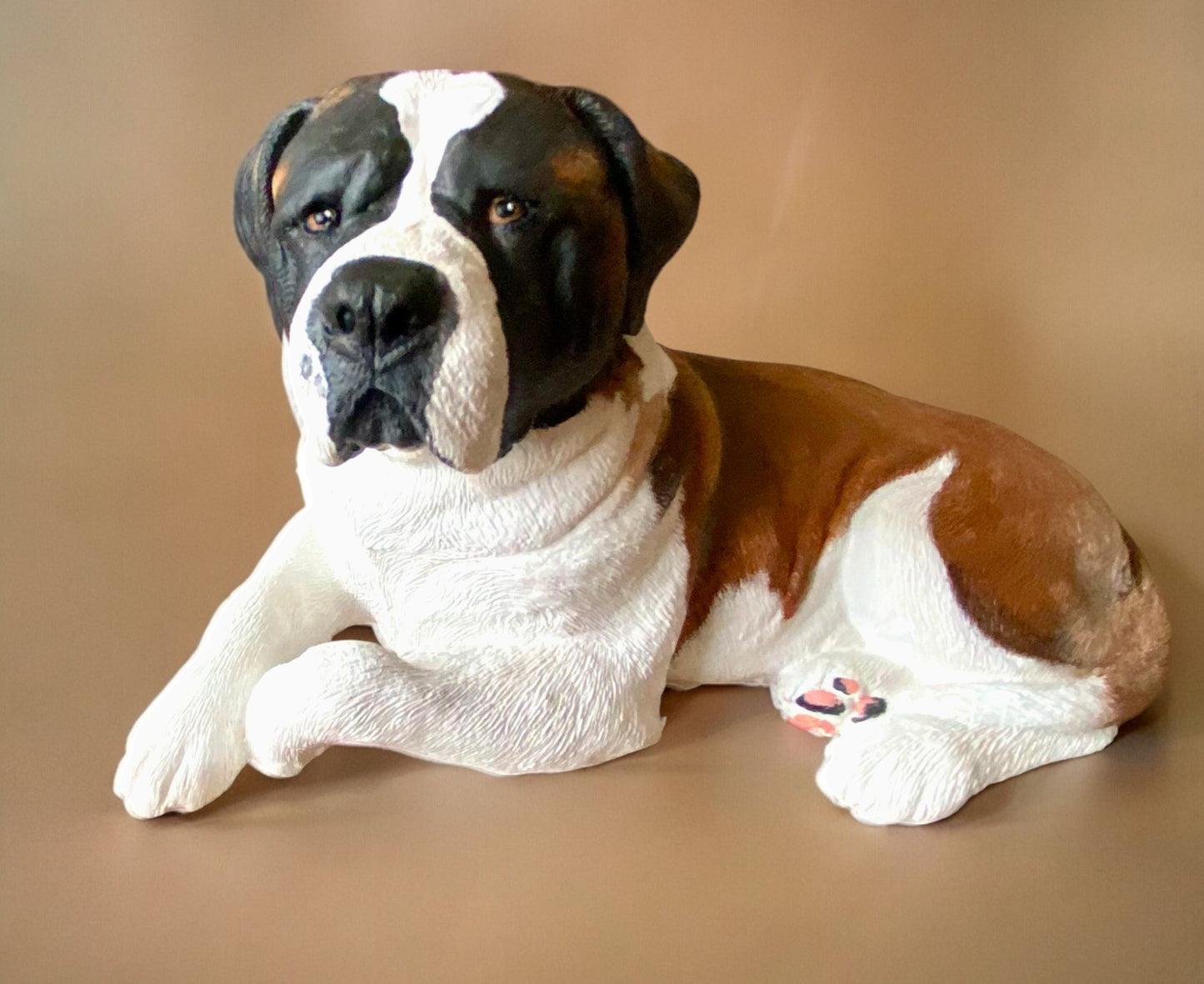 Saint Bernard statue made of concrete commissioned pet portrait of Charlie. Dog statue is laying down. Left side view of statue.