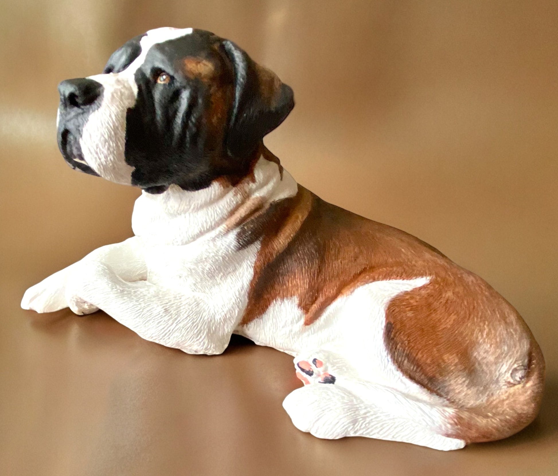 Saint Bernard statue made of concrete commissioned pet portrait of Charlie. Dog statue is laying down. Side view.